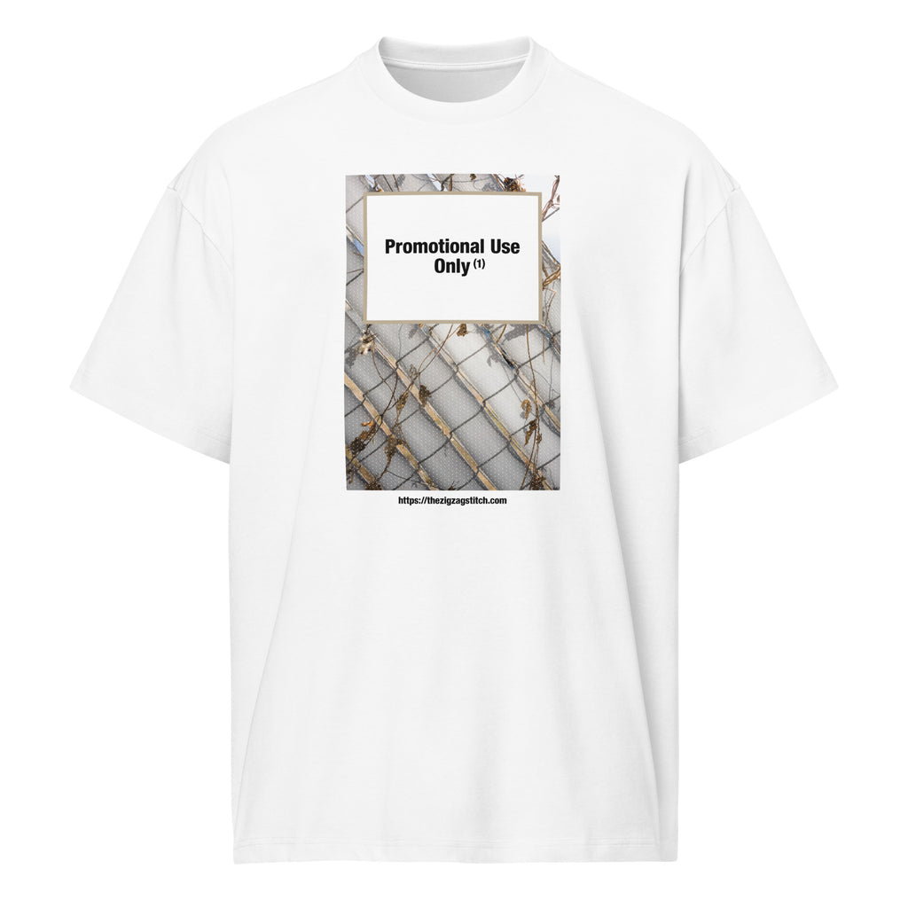 White graphic t-shirt featuring a print of a chain-link fence with dried vines. Centered text block reads “Promotional Use Only” designed by The Zigzag Stitch.