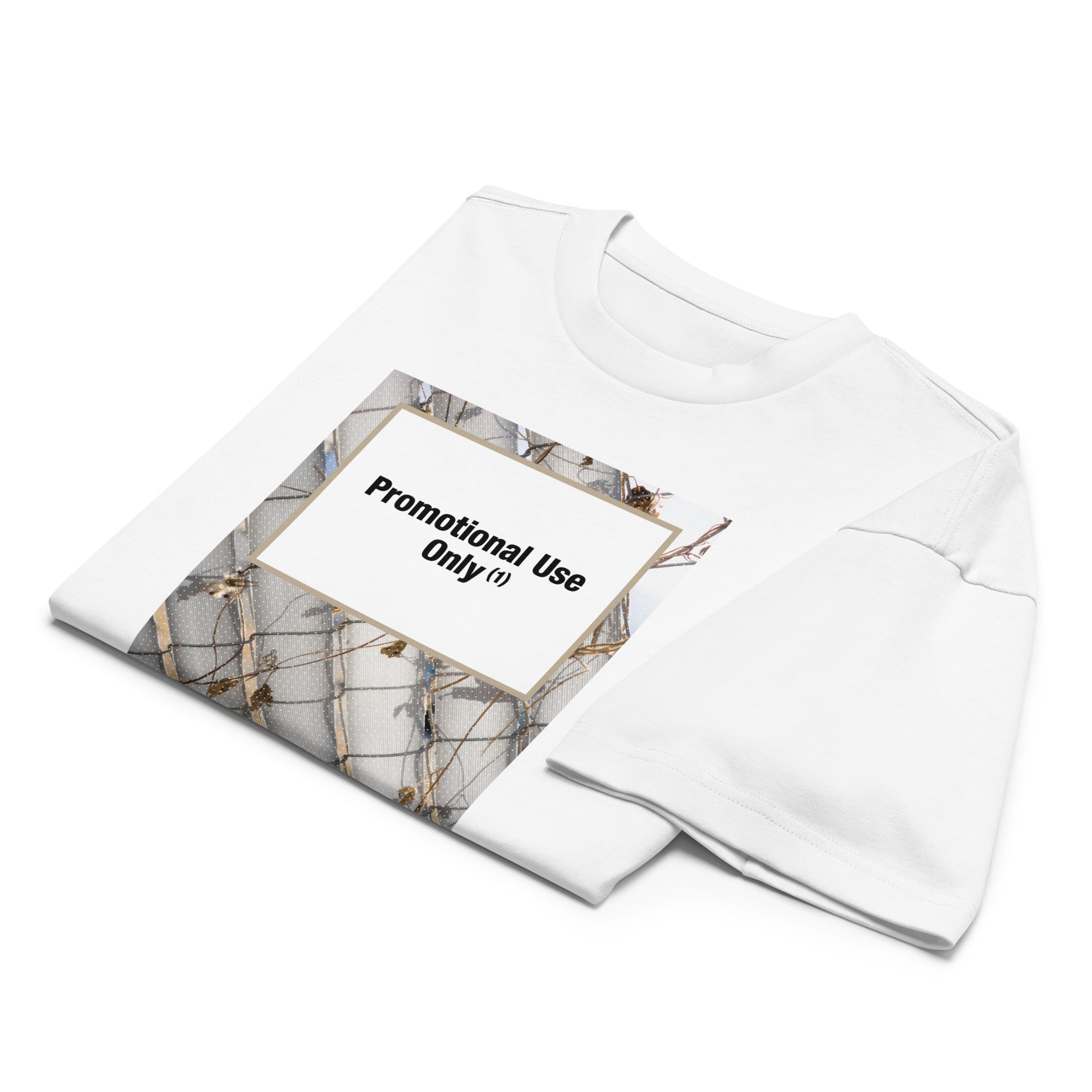 Folded white t-shirt with graphic design of chain-link fence and vines. Bold text overlay reads “Promotional Use” Contemporary streetwear by The Zigzag Stitch.