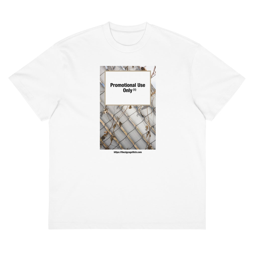 White t-shirt with graphic print of a chain-link fence covered in dried vines. Reads “Promotional Use Only” Designed by The Zigzag Stitch