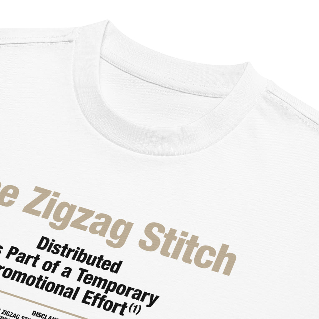Detail view of white t-shirt with graphic print. Reads “Distributed as Part of a Promotional Effort” designed by The Zigzag Stitch